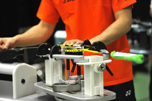 Nahaufnahme einer Person, die einen Tennisschläger auf einer Besaitungsmaschine vorbereitet.