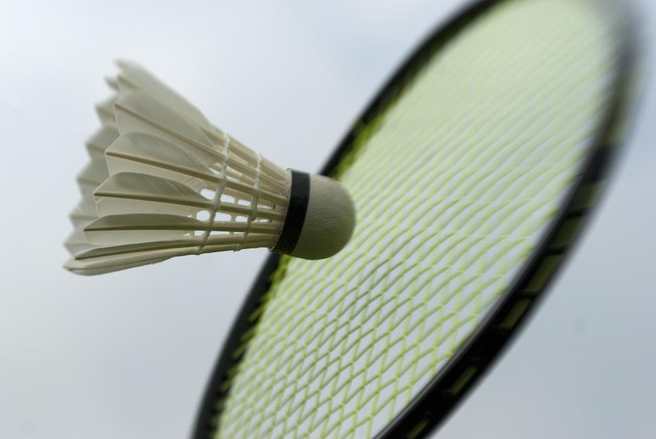 Nahaufnahme eines Federballs, der in Richtung eines Badmintonschlägers fliegt. Hintergrund unscharf.